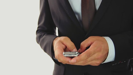 Hands of a businessman texting on a cell phone.