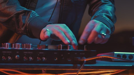 Hands of a DJ turning knobs on a turntable.