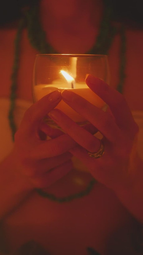 Hands of a girl holding a candle in the dark