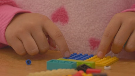 Hands of a girl playing with lego pieces