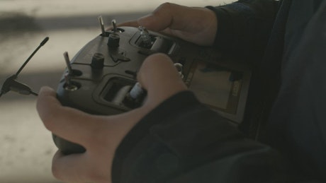 Hands of a man controlling a drone with a controller.