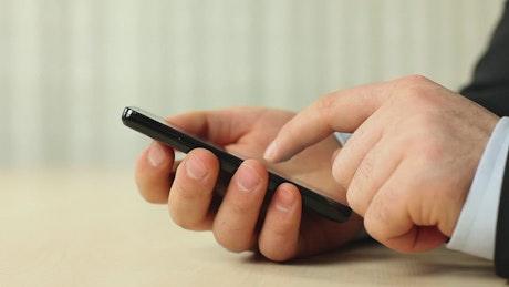 Hands of a man in a suit using his smartphone