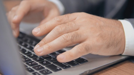Hands of a man typing on a laptop.
