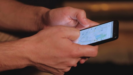 Hands of a person searching a map on his cell phone.