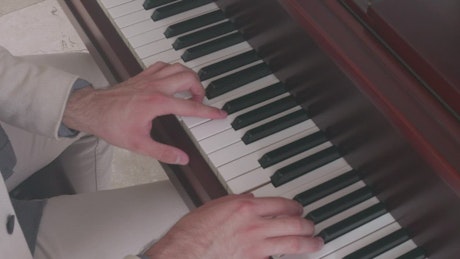 Hands of a pianist performing a song on a piano.
