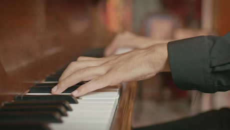 Hands of a skillful musician playing a wooden piano.