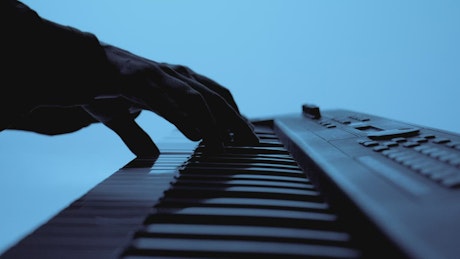 Hands of a talented pianist playing on a blue background.