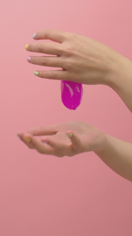 Hands of a woman playing with pink slime.