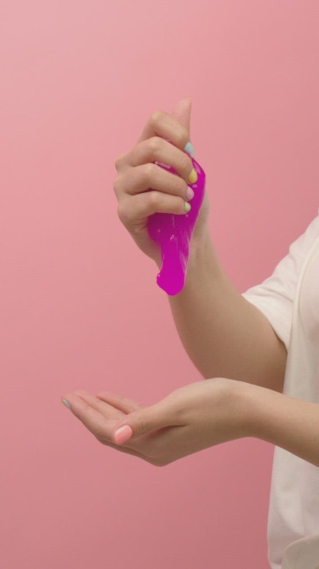 Hands of a woman playing with purple slime.
