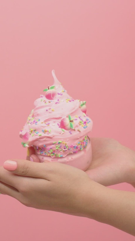 Hands of a woman showing ice cream shaped pink plasticine.