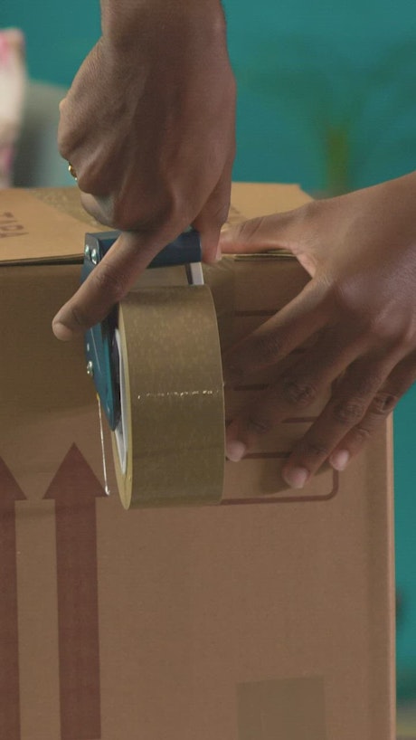 Hands of two people sealing a package with tape