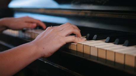 Hands playing an old classical piano