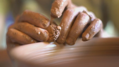 Hands working on pottery.