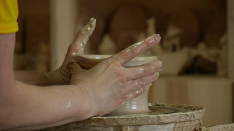 Hands working on raw ceramic