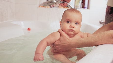 Happy baby being bathed in the tub