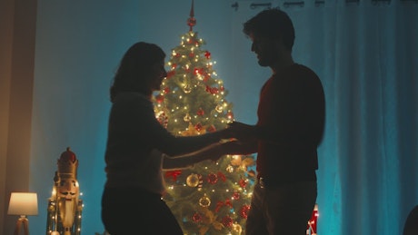 Happy couple dances by the Christmas tree.