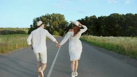 Happy couple running down a road.