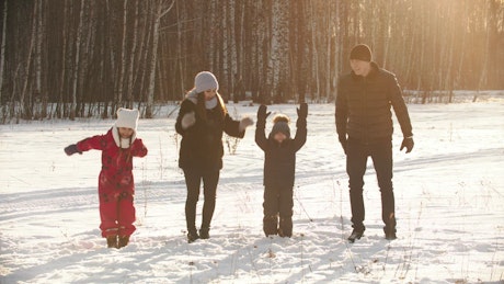 Happy family jumps in the snow in a forest.