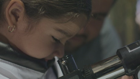 Happy father and daughter using a telescope.