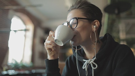 Happy urban woman sips coffee and listens to music