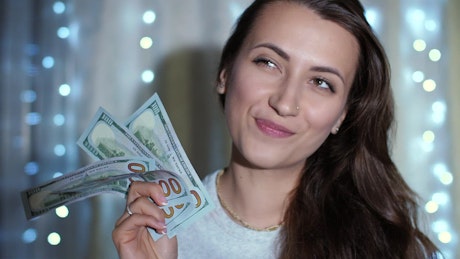 Happy woman imagining while holding bills.