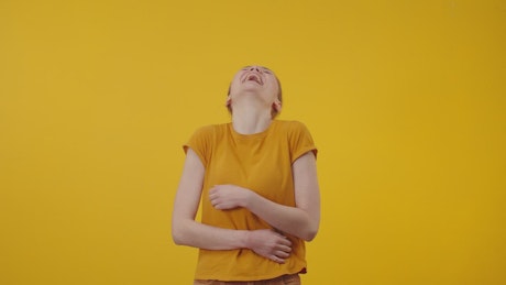 Happy woman in yellow laughing sincerely on a yellow background.