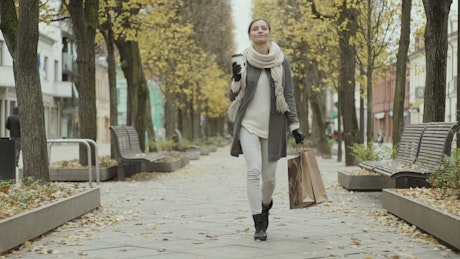 快乐的女人在秋天拿着购物袋散步