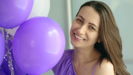Happy woman with purple and white balloons, portrait.