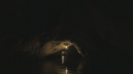 Heading through a dark cave by boat.