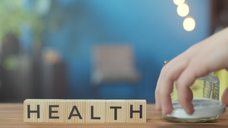 Health written on building blocks next to a jar of money.