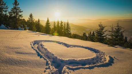 Heart shape in the snow mountains at sunset.