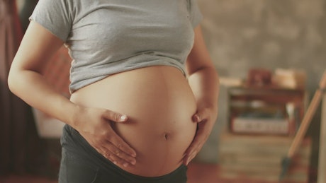 Heavily pregnant woman rubs her belly.