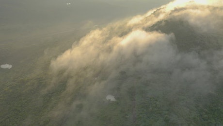 Hill covered with vegetation and mist seen from the air.