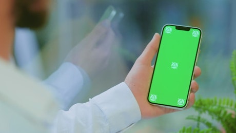 Holding a phone with a green screen and swiping.