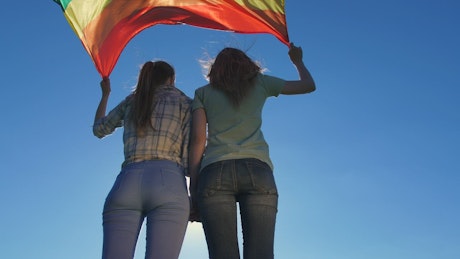 Holding a rainbow flag in the wind