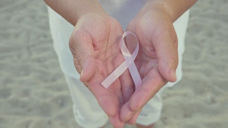 Holding the pink Cancer ribbon.