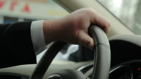 Holding the steering wheel of a car while driving.