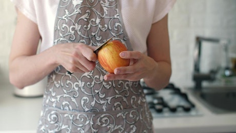 Housewife peeling an apple with a knife.