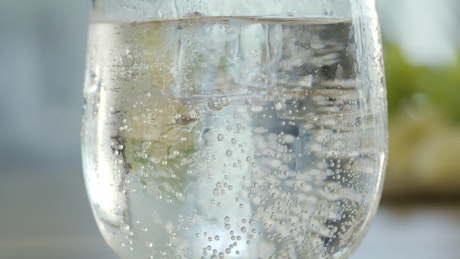 Ice cube drops into mineral water.