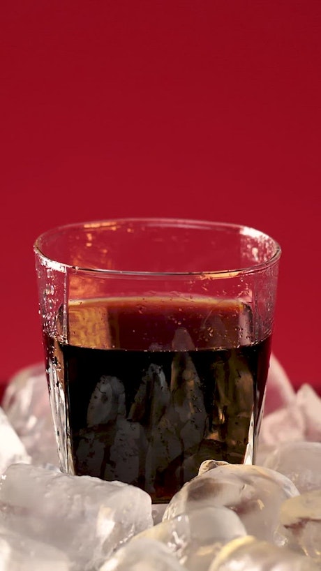 Ice falling into a glass with soda.