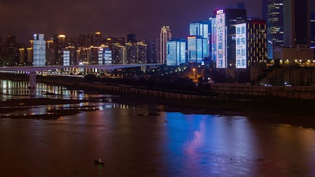 Illuminated and flashing buildings by the river.