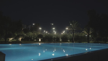 Illuminated hotel pool at night.