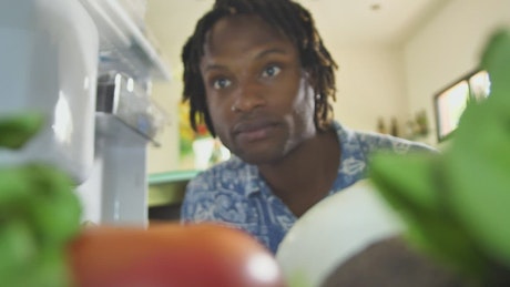 Inside view of a fridge when a man takes a lettuce