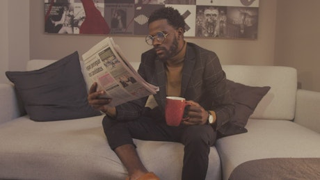 Intellectual man reading the newspaper with a cup of coffee.