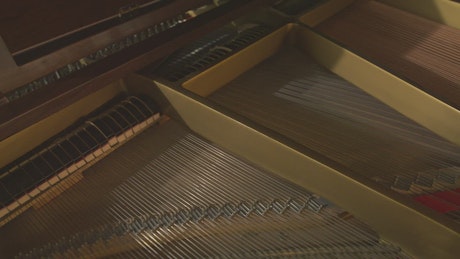 Interior of a grand piano while a musician plays.