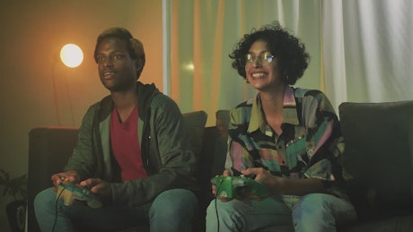 Interracial couple playing video games on the sofa.