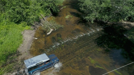 Jeep car crossing the river in the wilderness