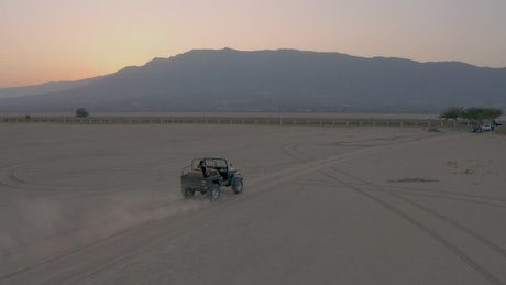 Jeep crossing a plain of land in an aerial shot.