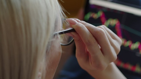 Lady putting on her glasses to see her investments.