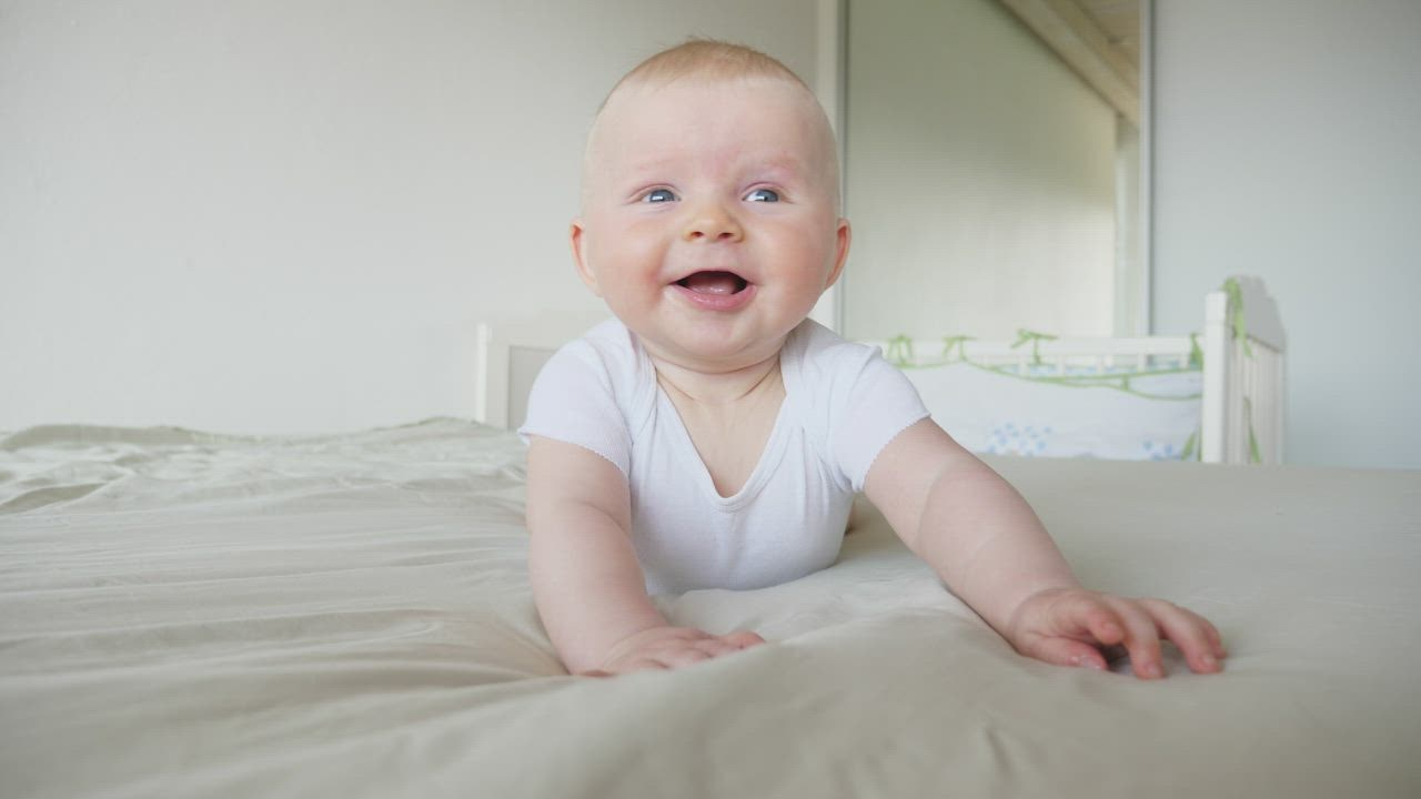 Laughing baby on bed in white room - Free Stock Video